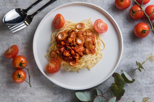 Spaghetti with tomato sauce and sausage in white plate on table top view