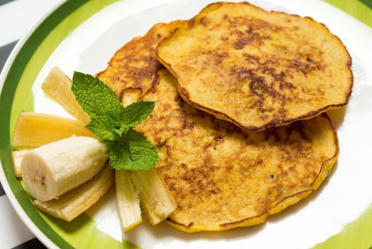 Delicious banana pancakes on a plate with green mint