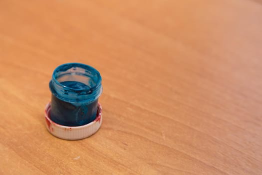 An open jar of used blue gouache for painting and creativity. Side view of a half-empty can of gouache paint. There is empty copy space.