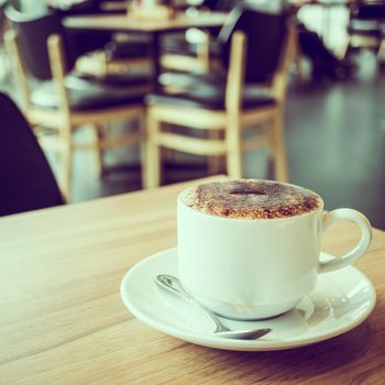 Cappuccino coffee in white cup on table in cafe - Vintage Filter