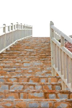 View from the bottom of a steep flight of brick steps with wooden railings leading up to the skyline