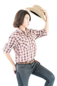 Young pretty woman in a cowboy hat and plaid shirt with hand on her hat isolated on white background