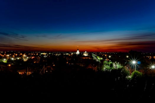 Evening panorama of the city on the background of sunset with a blue-maroon sky.The horizon line at dawn in the red sky.Panorama of the city with the sky line at night.Night streets with horizon line