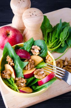 Spinach salad with nuts and apples served on table