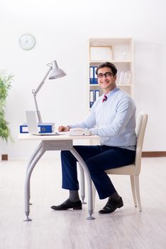 Young handsome businessman employee working in office at desk