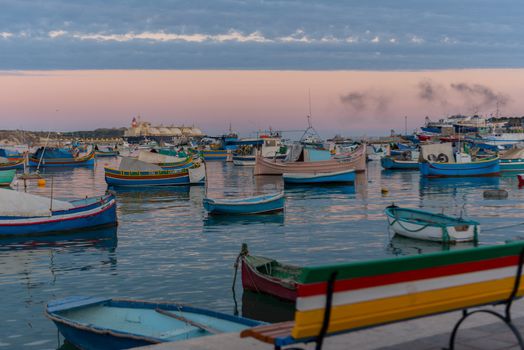 Traditional eyed colorful boats Luzzu in the Harbor of Mediterranean fishing village Marsaxlokk, Malta