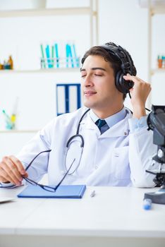 Happy excited doctor listening to music during lunch break in hospital