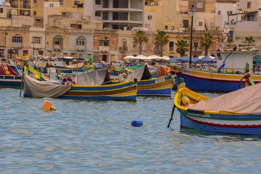Traditional eyed colorful boats Luzzu in the Harbor of Mediterranean fishing village Marsaxlokk, Malta