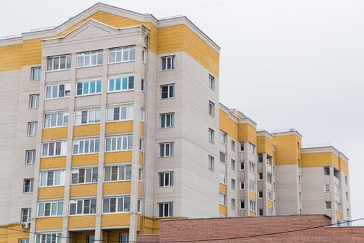 Residential high-rise brick buildings in a residential area of the city. Against the background of the gray sky. Modern new buildings, building facades. Real estate and urban architecture concept.