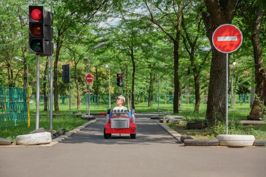 Safety traffic playground. Driving school kids education road rules. Small boy driving toy car stops at traffic lights on playground child learn traffic rules game road safety education children area