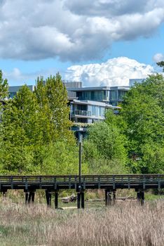 Eco cityscape. Wooden pier in front of residential building on cloudy sky background.