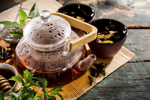 Beautiful Tea Ceremony Glass Teapot Honey Mint Cups on Old Rustic Green Table Background Closeup Horizontal