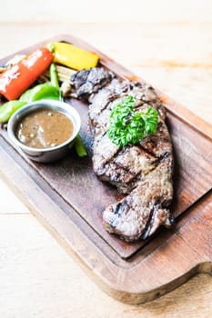Grilled beef steak with sauce and vegetable on wood cutting board