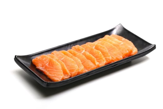 salmon slices in black plate on white background