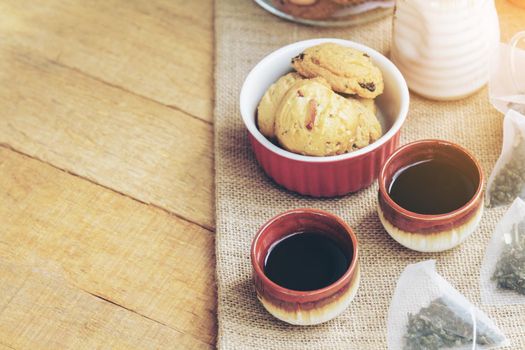 Tea with tea cup and cookie background barley rice grains and nature on wood table with copy space. Selective focus and soft flare sunlight. vintage tone.