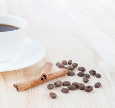 Coffee cup over wooden table with beans and cinnamon.