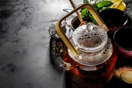 Beautiful Tea Ceremony Glass Teapot Honey Mint Lemon Cups on Dark Table Background Closeup Horizontal