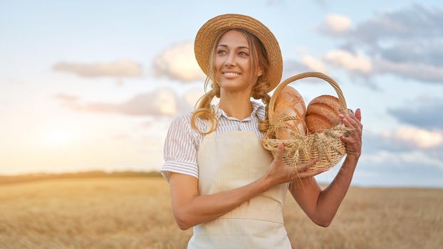 Woman baker holding wicker basket bread eco product Female farmer standing wheat agricultural field Baking small business Caucasian person dressed straw hat apron organic healthy food concept Banner