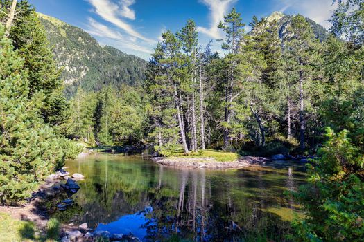 Scenic view of waterfall and lake in a Spanish Pyrenees Mountain in a sunny day. Transparent clear water.Aiguestortes i Estany of Saint Maurici National Park