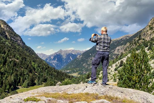 Middle aged tourist man take a picture from Spanish Pyrenees mountain with mobile phone
