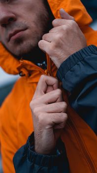 A man fastens his work uniform. Orange worker uniform - hands close up