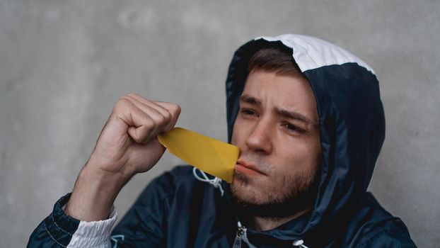 Man with tape over his mouth. The mouth is sealed with warning tape. Man tear off tape