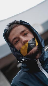 Man with tape over his mouth. The mouth is sealed with warning tape