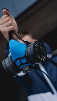 Protection respirator half mask for toxic gas.The man prepare to wear protection air pollution. Man holds a respirator, arm extended forward