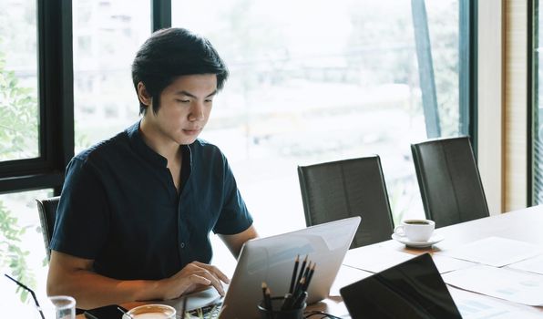 Young asian man working at home with laptop computer. Business Financial Concept.