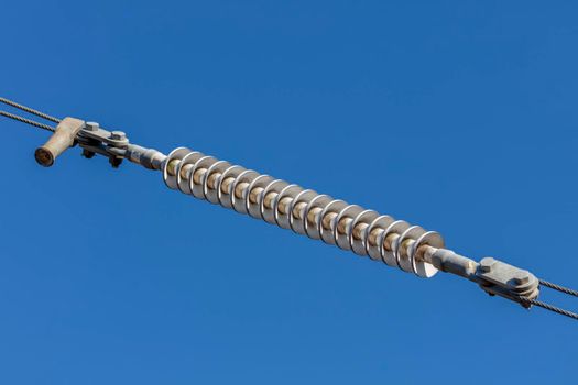 Photograph of a tensioner bracket on a transmission line against a bright blue sky