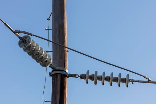 Photograph of a wooden telephone post and cables against a blue sky