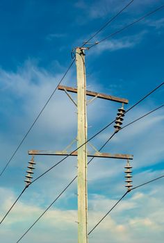 Photograph of a wooden telephone post and cables against a blue sky