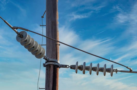 Photograph of a wooden telephone post and cables against a blue sky