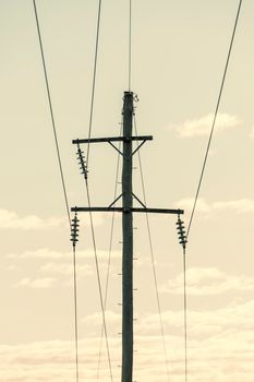 Photograph of a wooden telephone post and cables against a blue sky