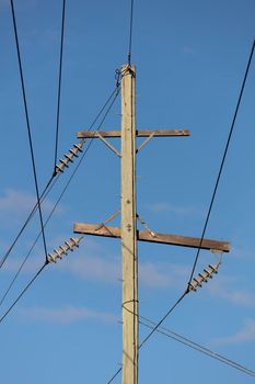 Photograph of a wooden telephone post and cables against a blue sky