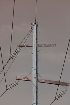 Photograph of a wooden telephone post and cables against a blue sky