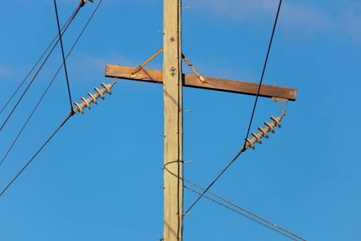 Photograph of a wooden telephone post and cables against a blue sky