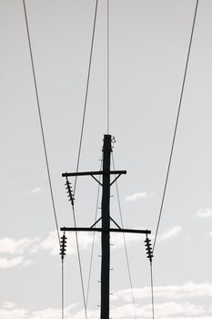 Photograph of a wooden telephone post and cables against a blue sky