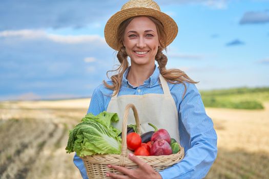 Woman farmer straw hat holding basket vegetable onion tomato salad cucumber standing farmland smiling Female agronomist specialist farming agribusiness Happy Girl dressed apron cultivated wheat field