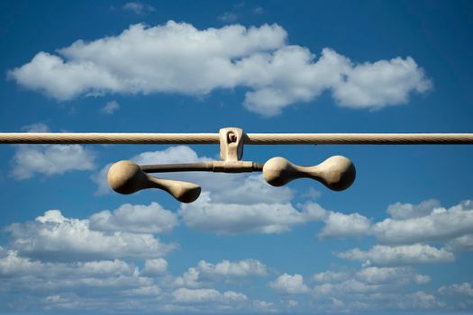 Photograph of a tensioner bracket on a transmission line against a bright blue sky