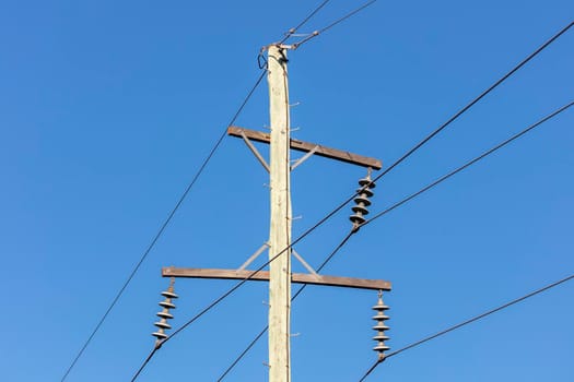 Photograph of a wooden telephone post and cables against a blue sky