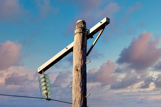 Photograph of a wooden telephone post and cables against a blue sky