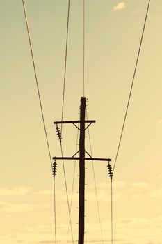 Photograph of a wooden telephone post and cables against a blue sky