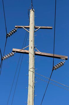 Photograph of a wooden telephone post and cables against a blue sky