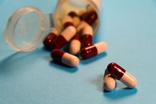 Capsule pills with spilled prescription drug pill container abstract on blue surface