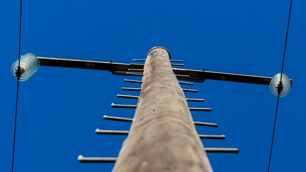 Photograph looking up a wooden telephone pole at the connection assembly in front of a blue sky