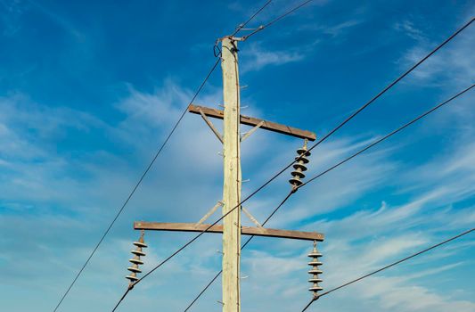 Photograph of a wooden telephone post and cables against a blue sky