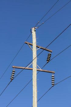 Photograph of a wooden telephone post and cables against a blue sky