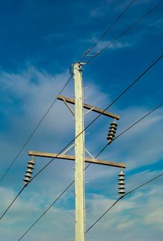 Photograph of a wooden telephone post and cables against a blue sky