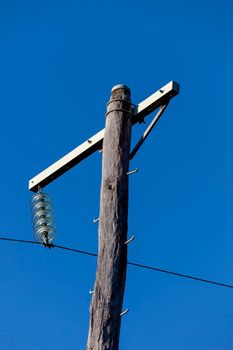 Photograph of a wooden telephone post and cables against a blue sky